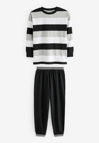 Chemise rayée à manches longues en gris, blanc et noir, associée à un pantalon de jogging noir avec des poignets rayés et une taille élastique.