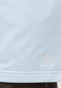 Világoskék pamut póló, kicsi, fehér hímzett Adidas logóval és alján varrott szegéllyel. Simább tapintású.