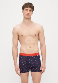 Tmavomodré boxerky s červenými vzormi srdiečok, s jasne červeným pásom s nápisom "HAPPY". Vyrobené z mäkkej a elastickej látky.