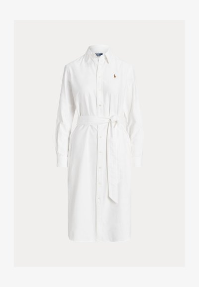 Fehér, hosszú ujjú, gombos ingruha gallérral, derékpánttal és kis hímzett logóval a bal mellrészen.