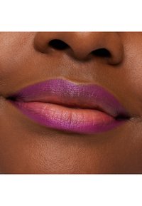 Lilla og rosa ombre leppestift påførte på fyldige lepper, med en jevn tekstur mot medium brun hudtone. Naturlig hudfinish synlig.