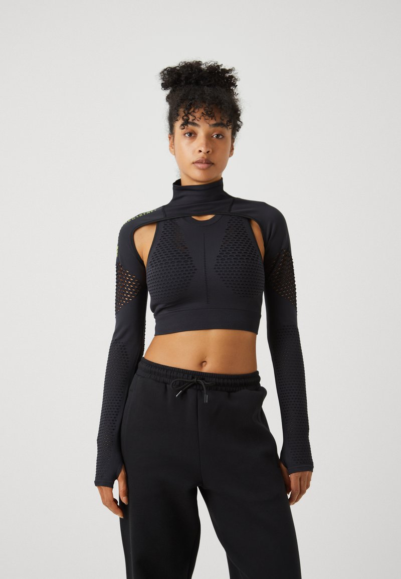 Fekete, hosszú ujjú crop top, textúrált kivágásokkal és állógallérral, fekete melegítőnadrággal párosítva, amely rugalmas derékrésszel rendelkezik.