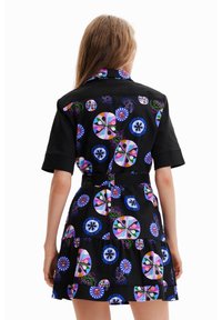 Czarna sukienka z krótkim rękawem, zdobiona kolorowym wzorem w kwiaty i geometrie. Zawiera pasek do wiązania oraz falbaniaste spódnice.