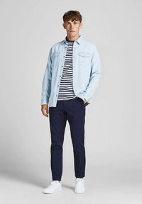 Chemise en denim bleu clair, t-shirt rayé blanc et marine, pantalon marine et baskets blanches. Coupe ajustée avec deux poches poitrine.