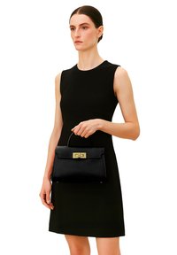 Borsa in pelle nera con un design strutturato, caratterizzata da un cappuccio frontale e una chiusura dorata. Texture liscia e una maniglia corta per il trasporto.