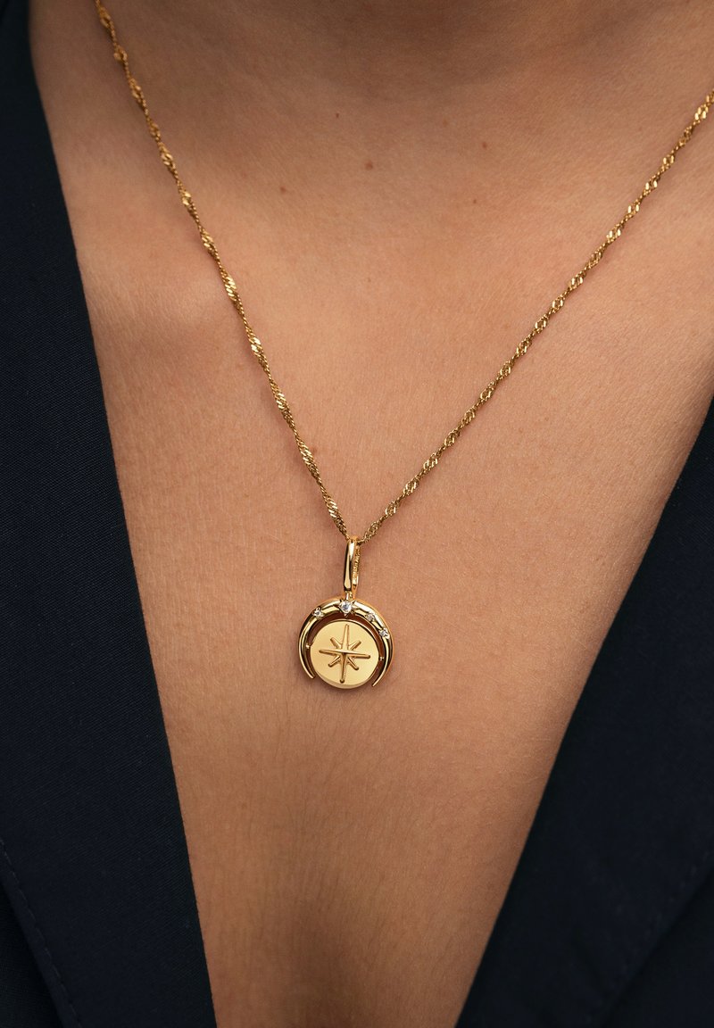 Collar de oro con cadena torcida y un colgante redondo con un diseño de estrella en relieve y decorado con una pequeña gema.