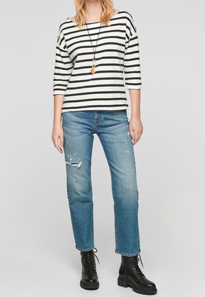 Schwarz-weißer, gestreifter Boot-Ausschnitt-Top mit dreiviertel Ärmeln, kombiniert mit distressed, hellblauen Jeans und schwarzen Schnürstiefeln.