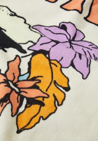 Blomstret fleece tekstil med store lilla, oransje og rosa blader på en kremfarget bakgrunn med svarte konturer, glatt tekstur.
