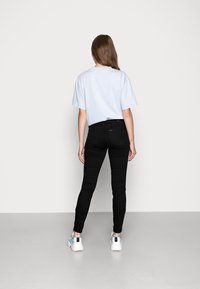 Camiseta de gran tamaño en azul claro, jeans skinny negros, zapatillas blancas con acentos azules. Diseño minimalista, ajuste casual, textura suave.