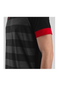 Polo shirt rayé noir et gris avec un accent rouge sur les manches. Fabriqué en tissu lisse, mettant en valeur un design ajusté et une texture douce.