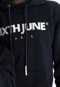 Sweat à capuche bleu marine avec texte blanc "SIXTH JUNE PARIS." Comprend une poche kangourou, une capuche avec cordon de serrage et des poignets côtelés. Tissu doux.