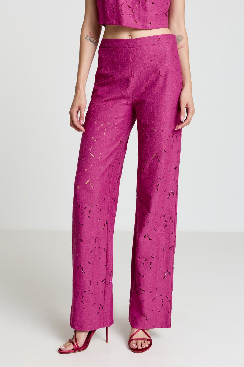 Pantalon taille haute fuchsia à motif en dentelle, coupe décontractée, associé à des talons à brides. Caractérisé par des découpes complexes et une texture lisse.