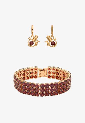 Aranyszínű ékszerszett, amely egy piros kövekkel díszített karkötőt és hozzá illő, egyedi macska sziluettjében készült fülbevalókat tartalmaz.