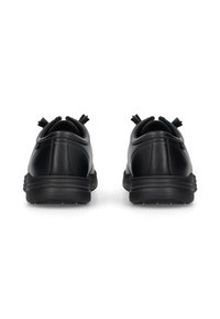 Ein Paar schwarze Ledersneaker, von hinten gezeigt, mit gepolsterten Kragen und dicken Gummisohlen auf einem weißen Hintergrund.