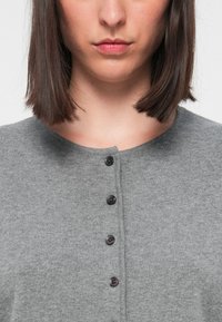 Cardigan gri din lână, cu guler rotund și cinci butoane negre pe față, având o textură moale și un design minimalist.