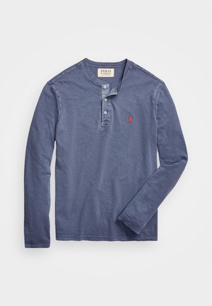 Long-sleeve, navy cotton henley shirt featuring a three-button placket and small red embroidered logo on the chest. Soft texture.