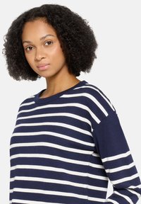Marineblauw-witte gestreepte trui met een geribde ronde hals, losse pasvorm en zachte textuur. Heeft brede horizontale strepen.