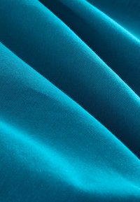 Turkooise katoenen stof met een gladde textuur, met plooien en verschillende tinten door de belichting. Goed gedefinieerd, horizontaal ribbelpatroon zichtbaar.