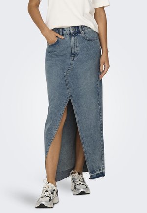 Denim maxi rok met een hoge split, lichtblauwe kleur, versleten zoom en voorkдет. Gestyled met een effen wit shirt en sneakers.