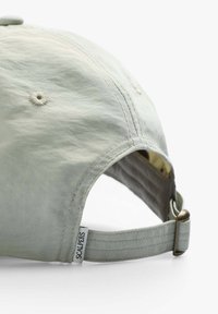 Light green baseball cap with a curved brim, adjustable strap, and stitching details. Features a visible brand tag on the side.