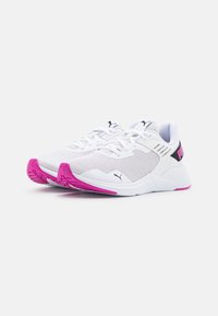 Białe buty sportowe z siateczkową cholewką, różowymi detalami na palcach i podeszwie, czarnym akcentem na pięcie oraz wyraźnym logo marki na boku.