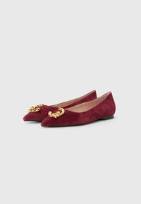 Bucșan de suede burgundy cu vârfuri ascuțite și un accent de lanț auriu în față. Prezintă o talpă joasă neagră și o căptușeală interioară netedă.