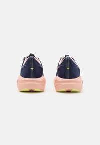 Baskets de sport navy et rose avec une tige en filet texturé, une semelle intermédiaire épaisse et une semelle en caoutchouc avec une accent vert au talon.