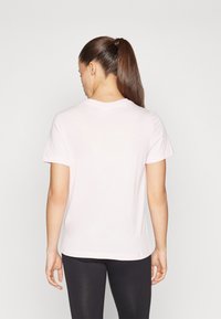 Lyserød bomulds T-shirt med korte ærmer, rund hals og en afslappet pasform, kombineret med sorte leggings. Enkel design, uden mønstre.