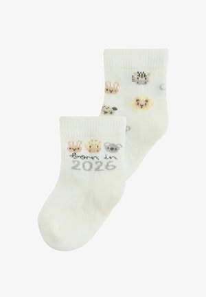 Chaussettes blanches pour bébé avec de petits visages d'animaux et le texte "Été 2023" en couleurs pastel douces sur le revers.