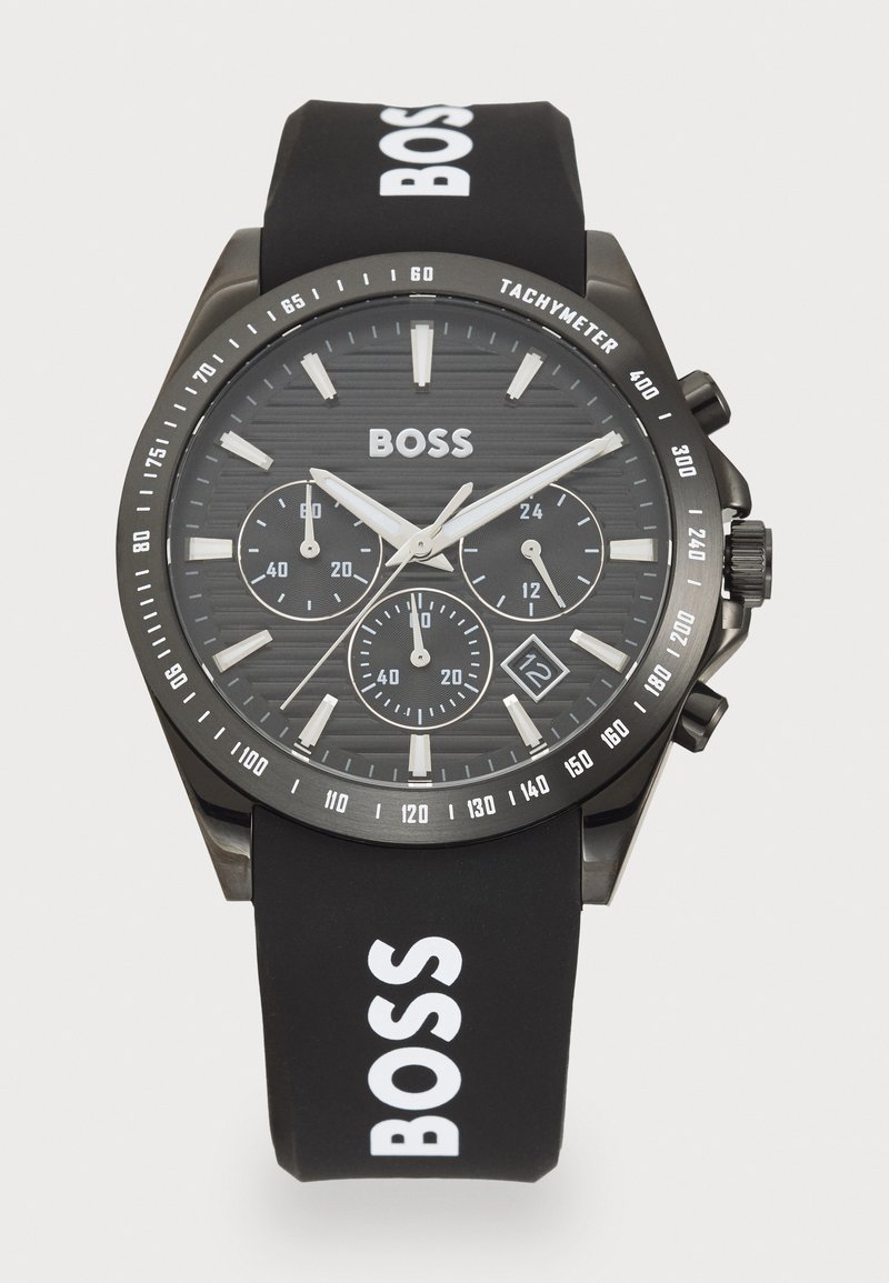 Black chronograph watch with a textured black dial, silver accents, and a rubber strap featuring white "BOSS" lettering. Date display at 6 o'clock.