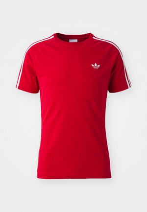 Red athletic t-shirt made of smooth fabric, featuring white shoulder stripes and a small white logo on the chest. Short sleeves, crew neck design.