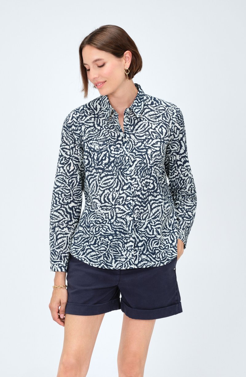 Camisa de manga larga con un patrón floral en navy y blanco, cuello abotonado y un corte relajado. Confeccionada en tejido ligero, de textura suave.