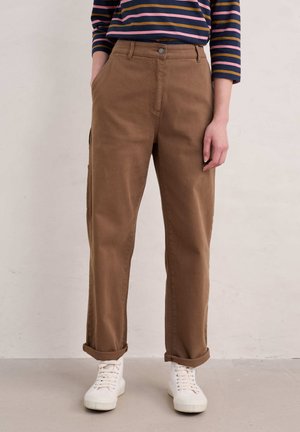 Bruine katoenen broek met een rechte snit, opgerolde manchetten en voorzakken, gecombineerd met witte sneakers en een gestreept longsleeve shirt.