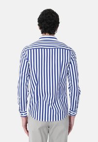 Camicia a maniche lunghe a righe verticali navy e bianche, realizzata in tessuto leggero, presenta un colletto a punta e polsini con bottoni.