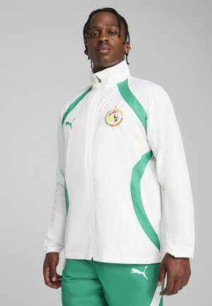 Witte sportjacket met groene accenten en een logo. Heeft een ritssluiting, hoge kraag en is gemaakt van lichtgewicht materiaal.