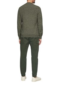 Groene gestructureerde sweater met lange mouwen, gecombineerd met olijfgroene cargobroek en witte sneakers, waardoor een casual achteraanzicht ontstaat.