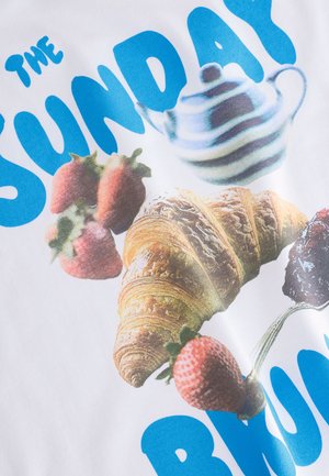 Biele tričko s grafickým dizajnom obsahujúcim modrý text "THE SUNDAY BRUNCH", jahody, hnedý croissant a prúžkovanú čajníkovú konvicu.