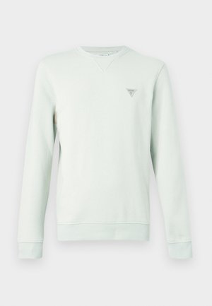 Heleroheline dressipluus pikkade varrukatega, ümara kaelusega ja väikese kolmnurkse logoga rinnal. Pehme kangas ja soonikkoes varrukaservad.