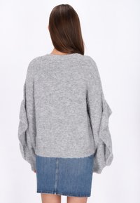 Szary, teksturowany sweter z luźnymi rękawami, zestawiony z dżinsową mini spódnicą. Miękki, dzianinowy materiał charakteryzuje się swobodnym krojem i okrągłym dekoltem.