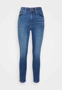 Höga blå skinny jeans med två knappar, framfickor och en klassisk denimtextur, visade mot en enkel vit bakgrund.