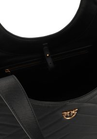Black leather handbag with a quilted design, featuring a gold-toned hardware accent and an interior zip pocket for secure storage.