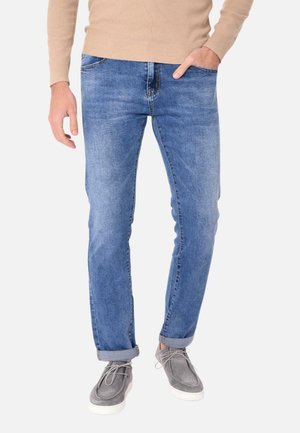 Jeans in denim azzurro chiaro da uomo con vestibilità slim, dotati di un classico design a cinque tasche e orli arrotolati, abbinati a scarpe grigie.
