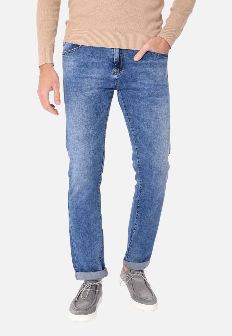 Jeans in denim azzurro chiaro da uomo con vestibilità slim, dotati di un classico design a cinque tasche e orli arrotolati, abbinati a scarpe grigie.