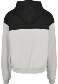 Hooded sweatshirt with a black upper panel and light gray lower section. Made of soft fabric with ribbed cuffs and hem.