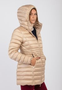 Beige, puffy jack met een capuchon, voorzien van een rits aan de voorkant, zijzakken en een quilted ontwerp. Gladde textuur met een glanzende afwerking.