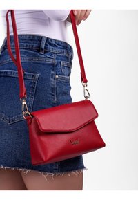 Červená kožená přes rameno s pevným tvarem, hladkým povrchem a klopovým uzavřením. Obsahuje zlaté kovové detaily a nastavitelný popruh.