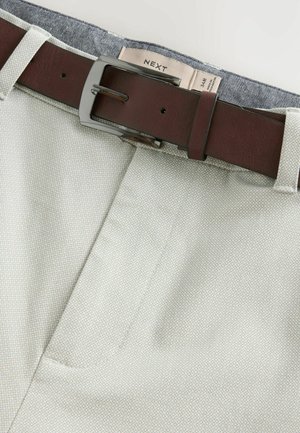 Beige pants with a textured pattern, featuring a brown leather belt and metal buckle, showcasing a two-tone interior detail.