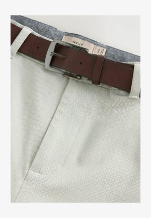 Pantalones beige con un patrón texturizado, que cuentan con un cinturón de cuero marrón y hebilla de metal, mostrando un detalle interior bicolor.