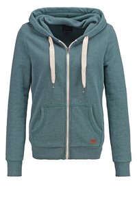 Felpa con zip color teal, dotata di cappuccio, cordini color crema, due tasche frontali e polsini a costine. Presenta una piccola etichetta con il marchio nella parte anteriore inferiore.