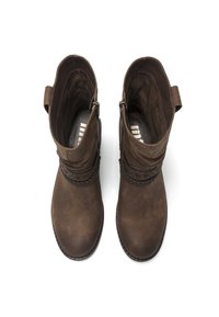 Brązowe zamszowe botki za kostkę z dekoracyjnymi plecionymi akcentami, bocznymi zamkami błyskawicznymi i teksturowanym wnętrzem, widziane z góry.